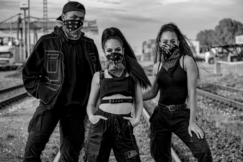a group of people standing next to each other on a train track, an album cover, pexels contest winner, afrofuturism, black bandana mask, 2 techwear women, studio shot, 3 - piece