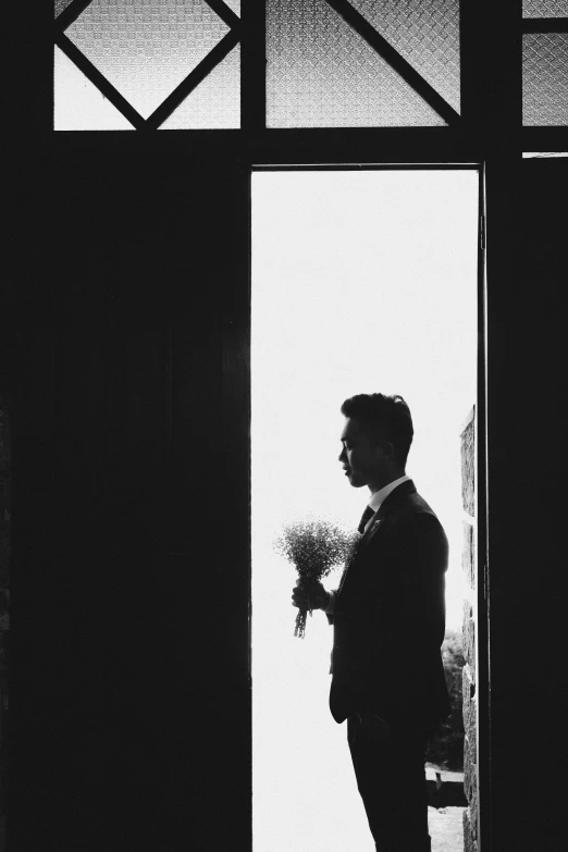 a black and white photo of a man holding a bouquet, by Alexis Grimou, unsplash, romanticism, door, groom, silhouettes, instagram picture