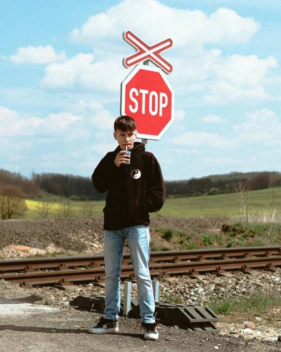 a man standing in front of a stop sign, trending on pexels, yung lean, rail tracks, instagram model, teenage no