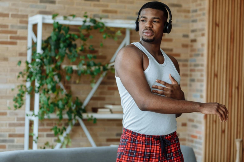 a man standing in a living room wearing headphones, trending on pexels, loin cloth, avatar image, jaylen brown, health supporter