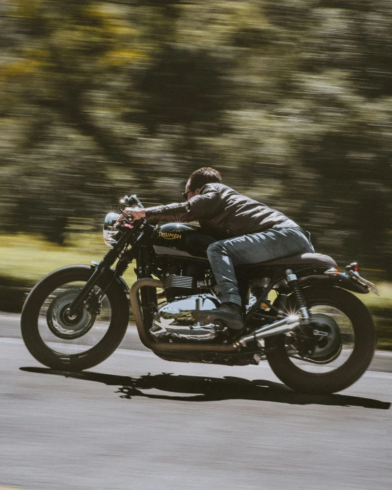 a man riding on the back of a motorcycle down a road, profile image, triumph, melbourne, unsplash photography