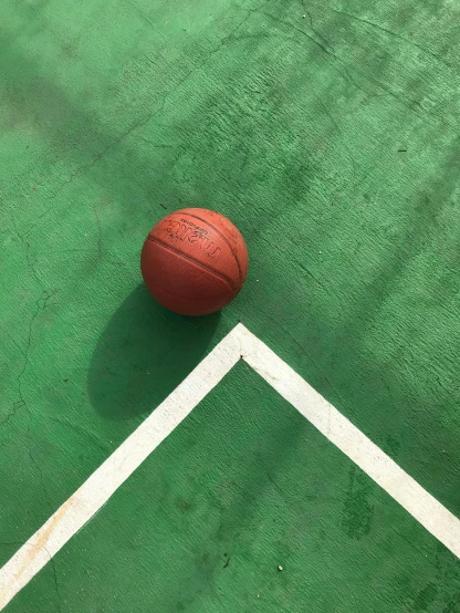 a basketball ball sitting on top of a green court