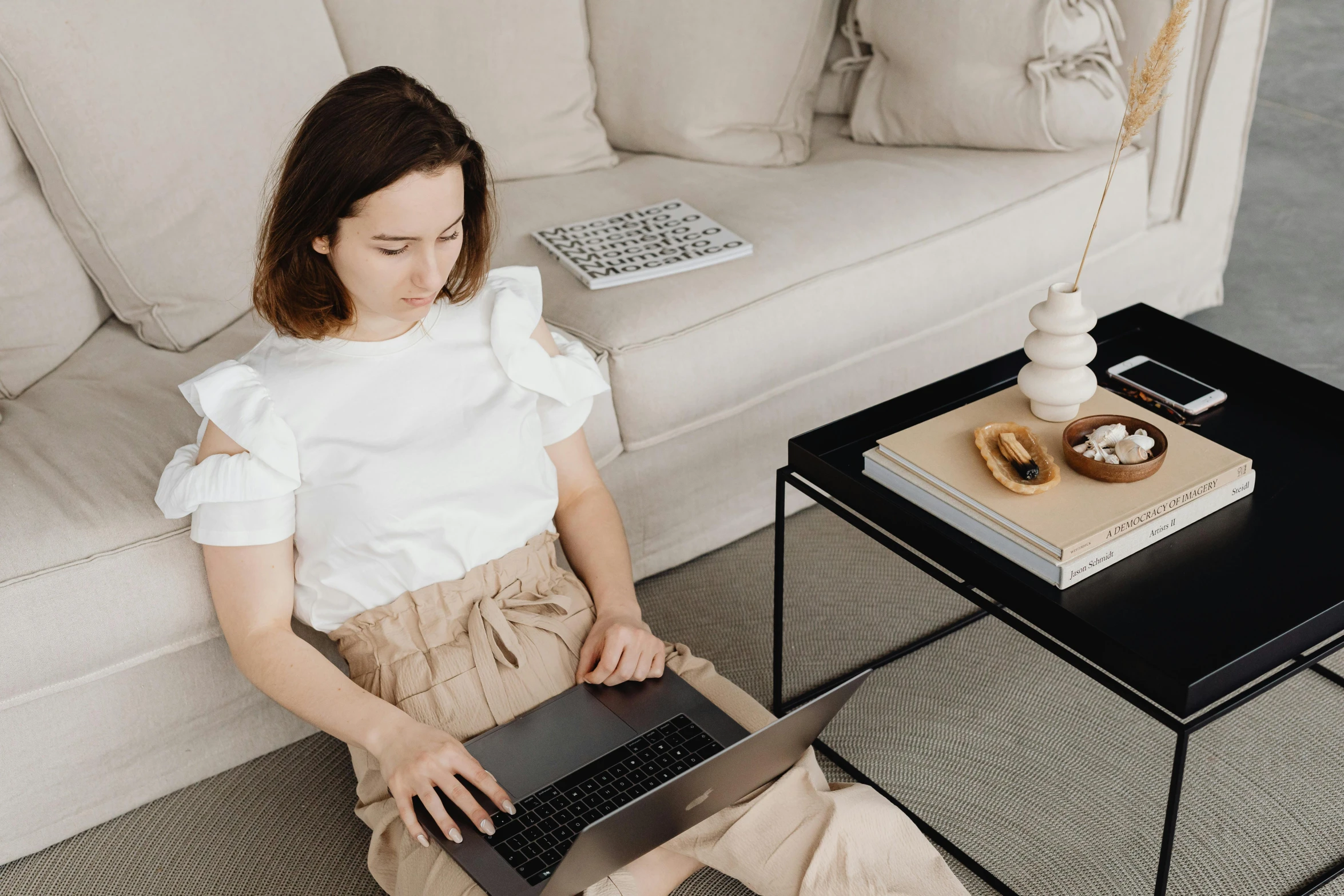 a woman sitting on a couch using a laptop, trending on pexels, office clothes, brown and white color scheme, fantasy medium shot, thumbnail