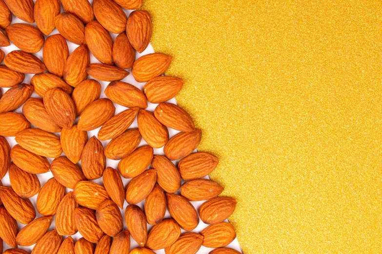a pile of almonds on a yellow background, an album cover, pexels, golden fabric background, orange color, background image, on a white background