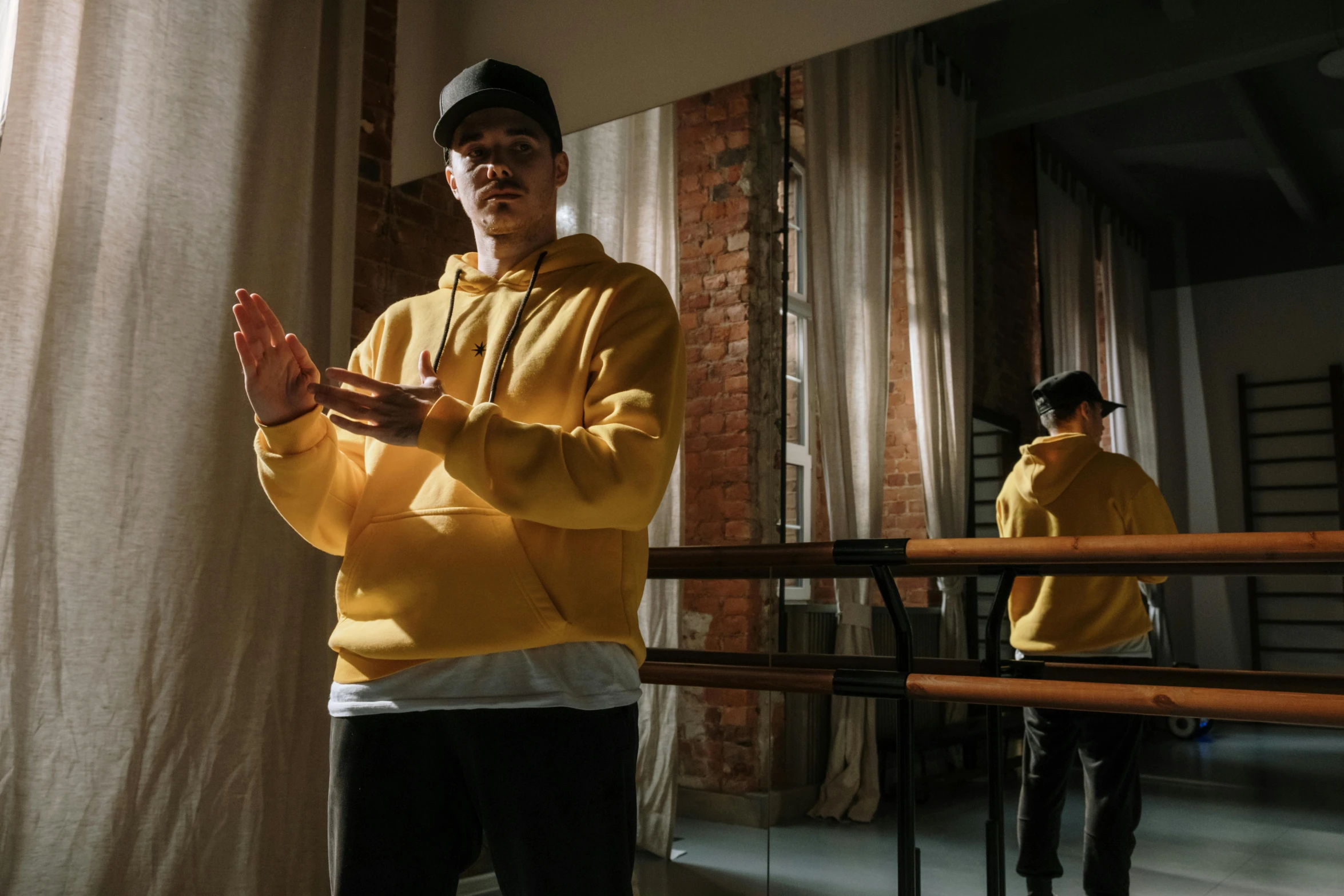 a man in a yellow hoodie standing in front of a mirror, inspired by Ma Quan, pexels contest winner, dancer, avatar image, ( ( theatrical ) ), baggy clothing and hat