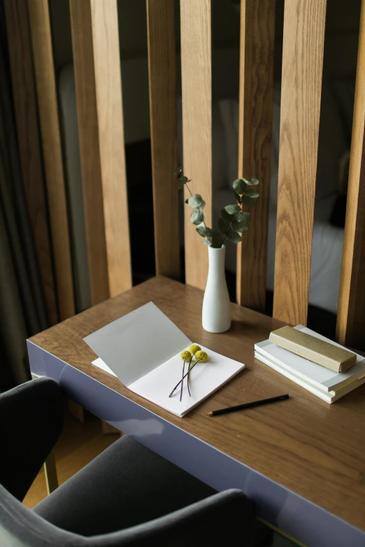 a table with a book, flower and a vase on top