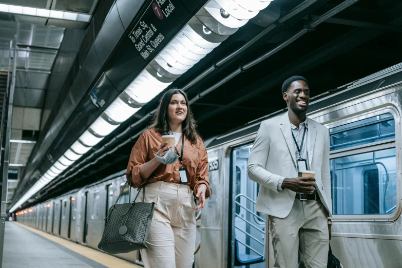 a couple of people standing next to a train, subways, brown and white color scheme, carrying a tray, portrait featured on unsplash