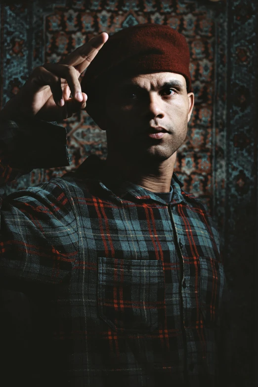 a black man poses with his hands up in a dark room