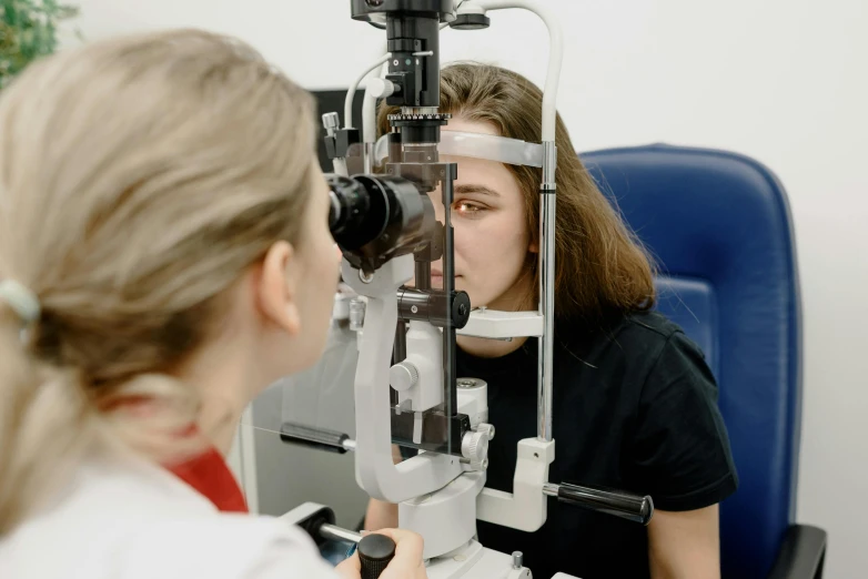 a woman getting her eye examined by a doctor, a picture, lachlan bailey, medium level shot, forward facing, pupil