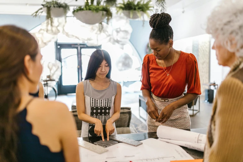 a group of women standing around a table, pexels contest winner, blue print, best of retail, 9 9 designs, looking her shoulder