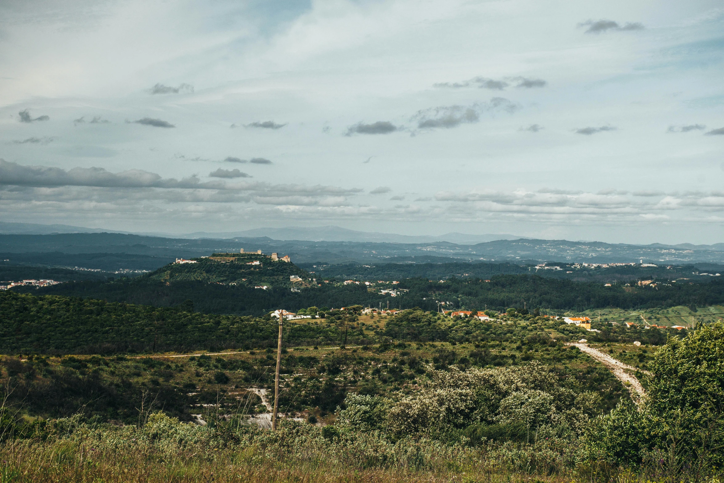 a grassy field that has a hillside in the distance