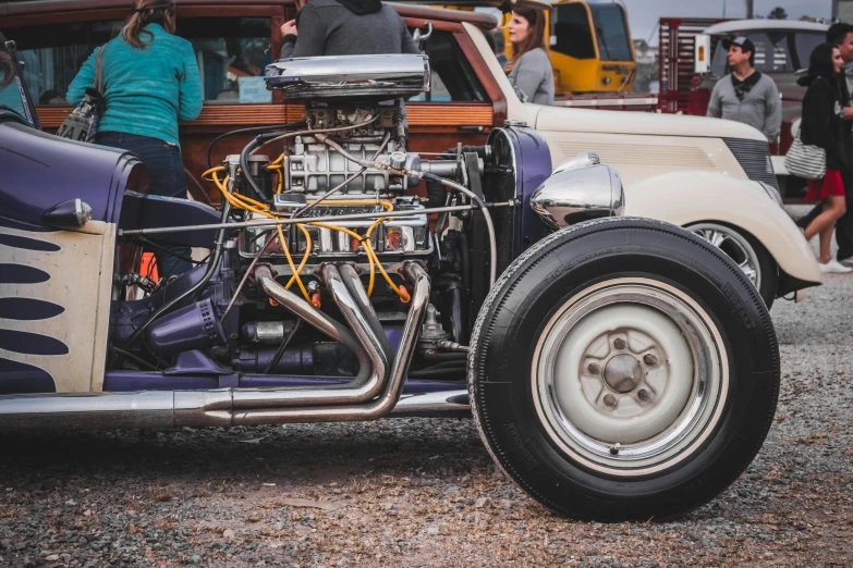 a group of people standing around a vintage car, pexels contest winner, auto-destructive art, pistons and bolts, rat fink style, featuring engine, instagram picture