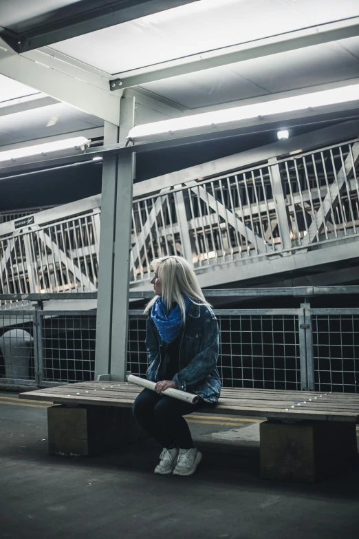 a woman sitting on a bench in a train station, inspired by Elsa Bleda, unsplash contest winner, graffiti, girl with white hair, sitting under bridge, low - lighting, reading