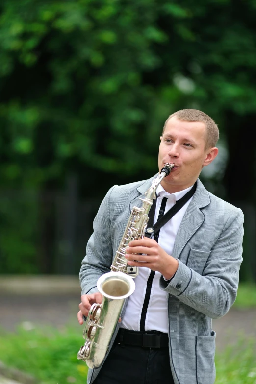 a male with a suit and tie plays the saxophone