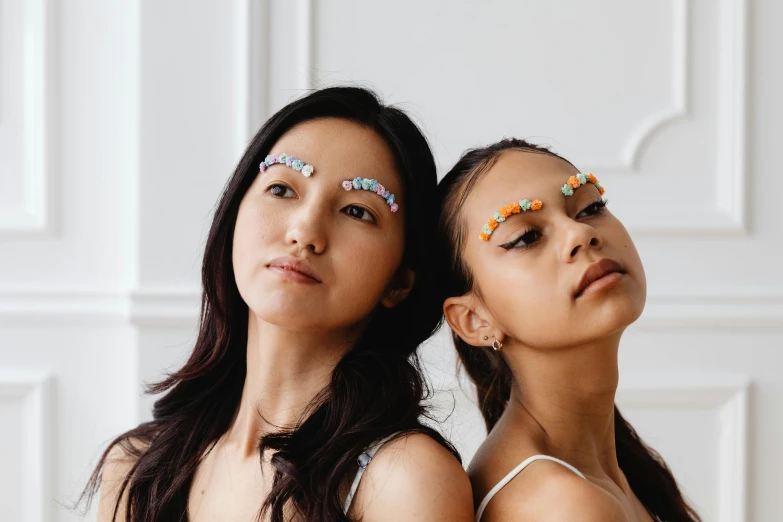a couple of women standing next to each other, inspired by Wang Duo, trending on pexels, antipodeans, jeweled ornament over forehead, they are all laying down, stickers, bella poarch
