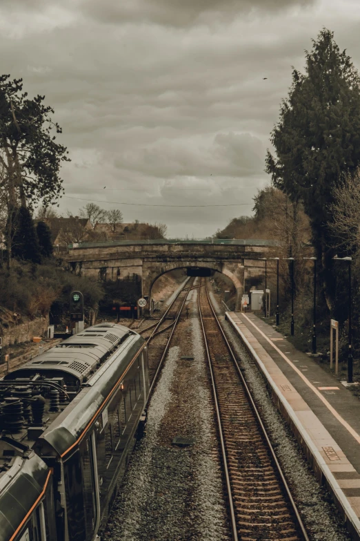 a train traveling down train tracks next to a train station, by James Morris, unsplash, renaissance, esher, panoramic, low quality photo, thumbnail