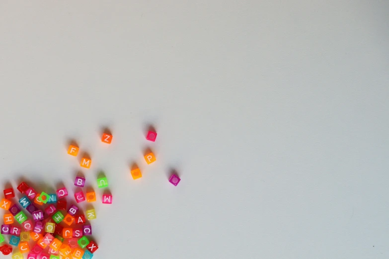 small colorful dices scattered together in the middle of a white table