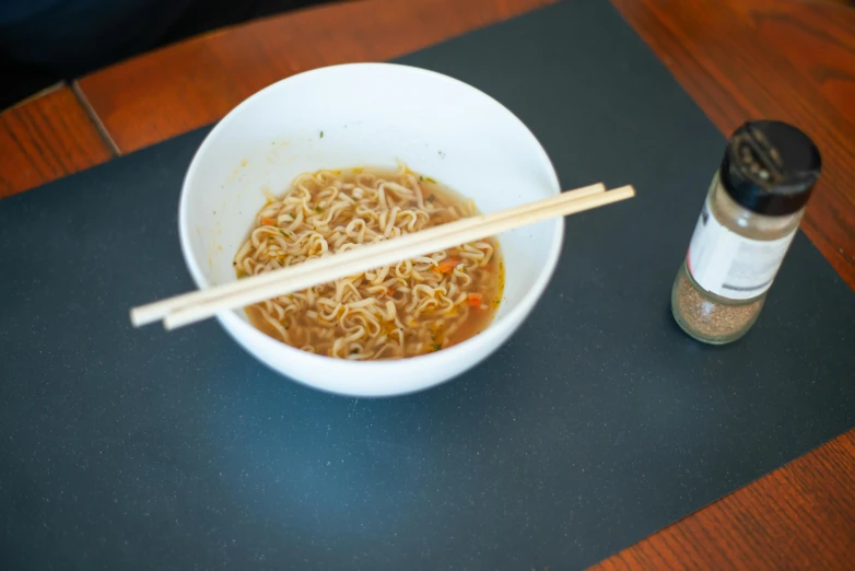 a bowl of noodles and chopsticks on a table, by Matthias Stom, pexels contest winner, sōsaku hanga, square, good soup, made of glazed, gold