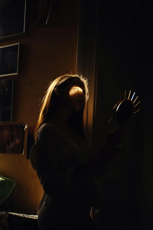 a woman standing in front of a window in a dark room, with the sun shining on it, with a mirror, poorly lit, ;cinematic lighting