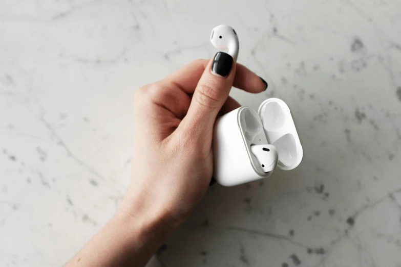 a person holding an airpods in their hand, by Emma Andijewska, trending on pexels, porcelain skin ”, square, “hyper realistic, white mechanical details