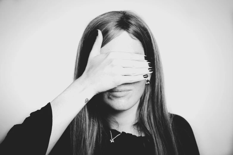 woman with hand on forehead covering face with fingers