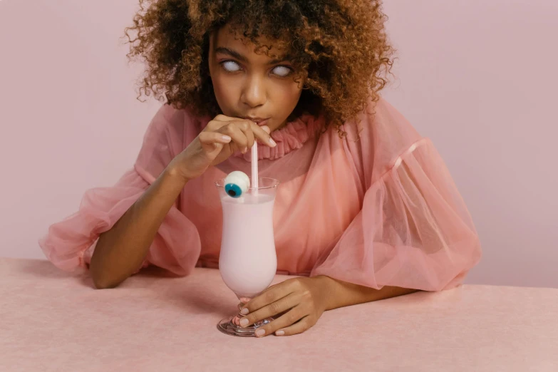 a woman with an evil eye holding a milkshake