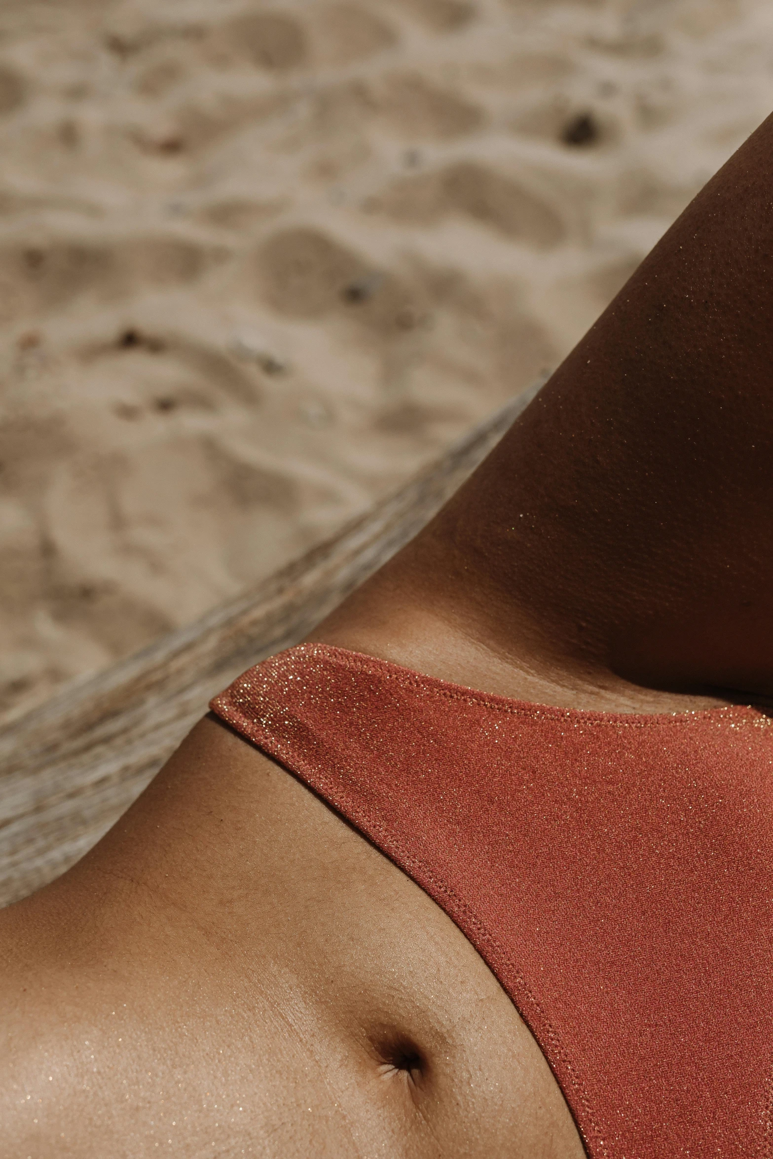 a woman in a bikini laying on a beach, by Nina Hamnett, trending on pexels, renaissance, skin grain detail, copper, solid colours, detail shot