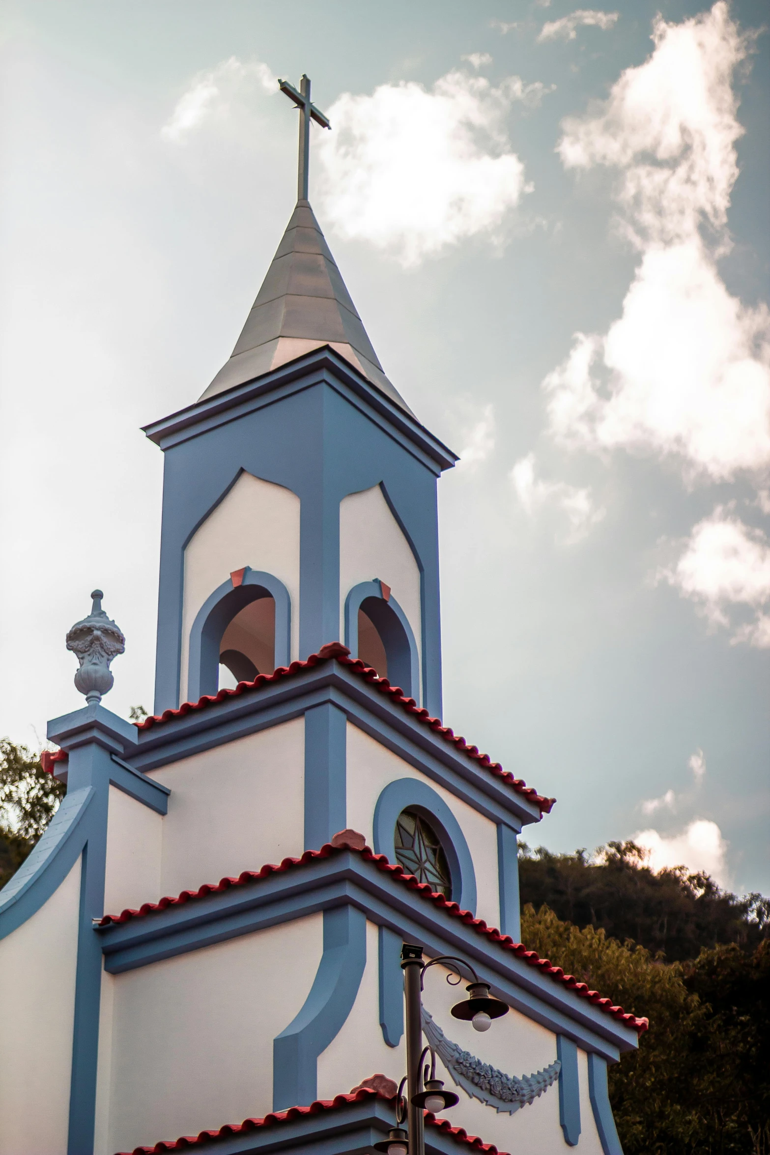 a blue and white church with a cross on top, red roofs, vallejo, heraldo ortega, pointy conical hat