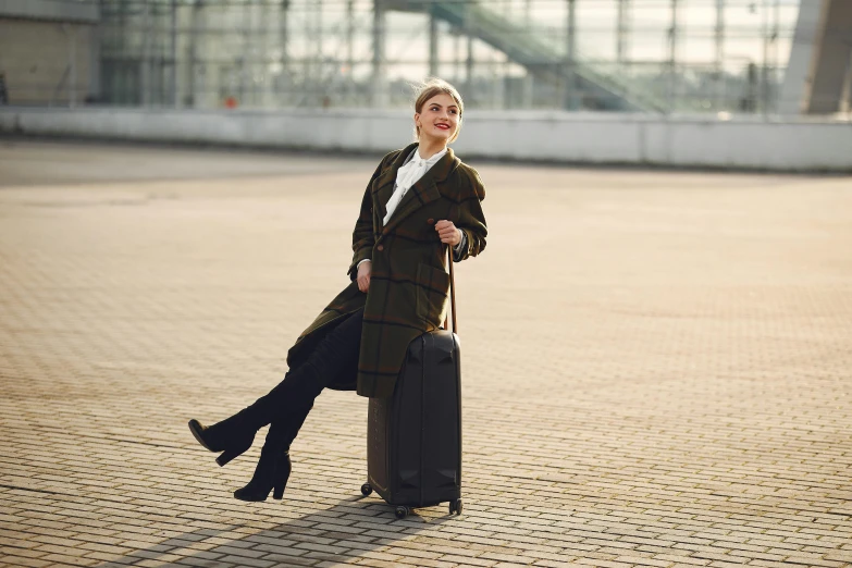 a woman sitting on top of a piece of luggage, wearing black coat, influencer, knee-high boots, post graduate