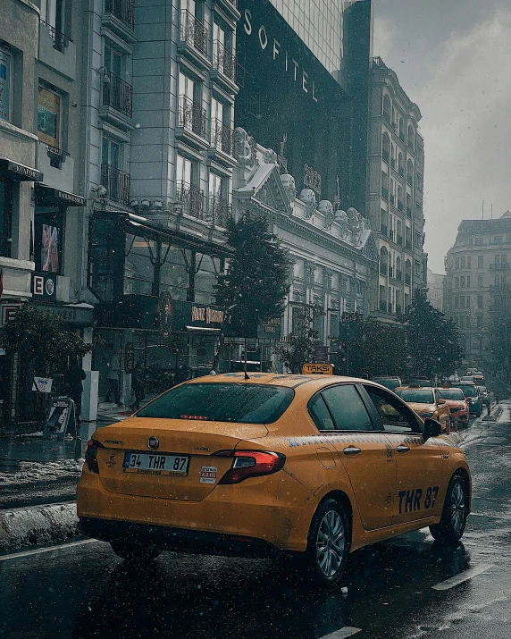 a yellow taxi is stopped on a city street in the snow