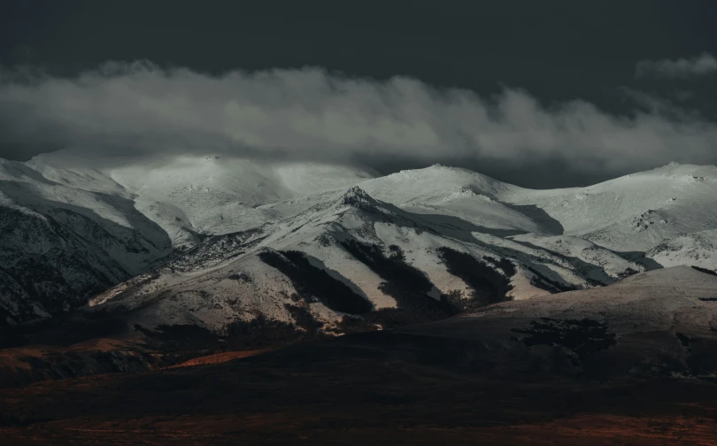 an airplane flies over some snowy mountains under a dark sky