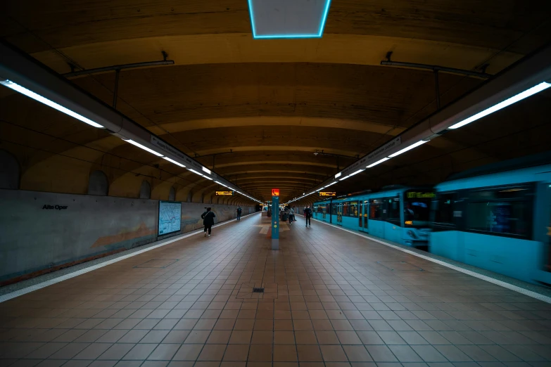 a train pulling into a train station next to a platform, by Jens Søndergaard, unsplash, hyperrealism, blue lamps on the ceiling, people on the ground, cyan and orange, dark underground