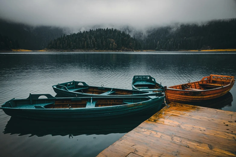 a couple of boats sitting on top of a lake, pexels contest winner, gloomy mood. greg rutkowski, in a row, serene colors, whistler