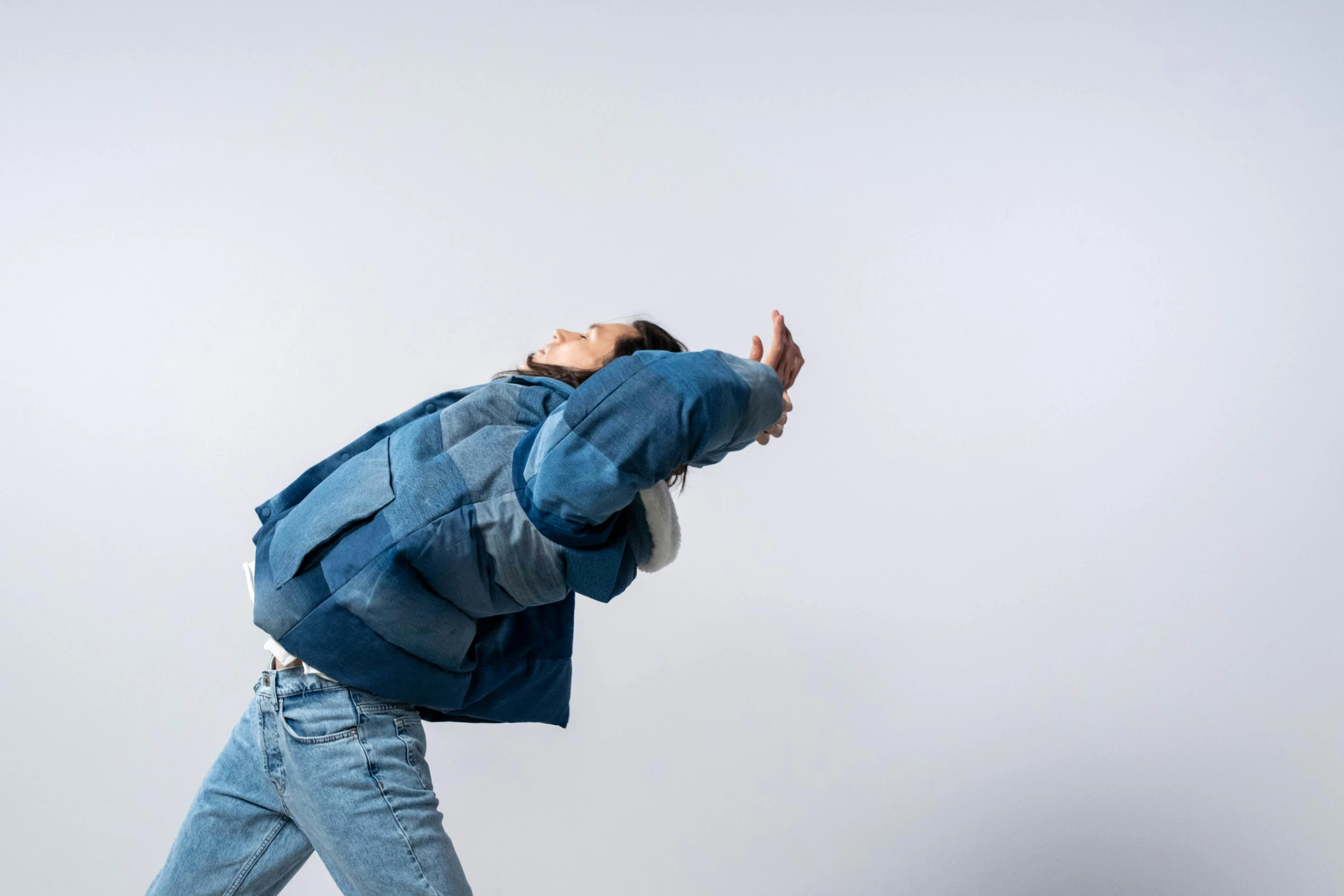 a person walking while wearing a blue jacket and jeans