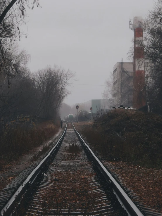 a train track surrounded by trees on a foggy day, an album cover, inspired by Elsa Bleda, unsplash contest winner, realism, abandoned buildings, in empty!!!! legnica, low quality footage, cinematic photo 4k