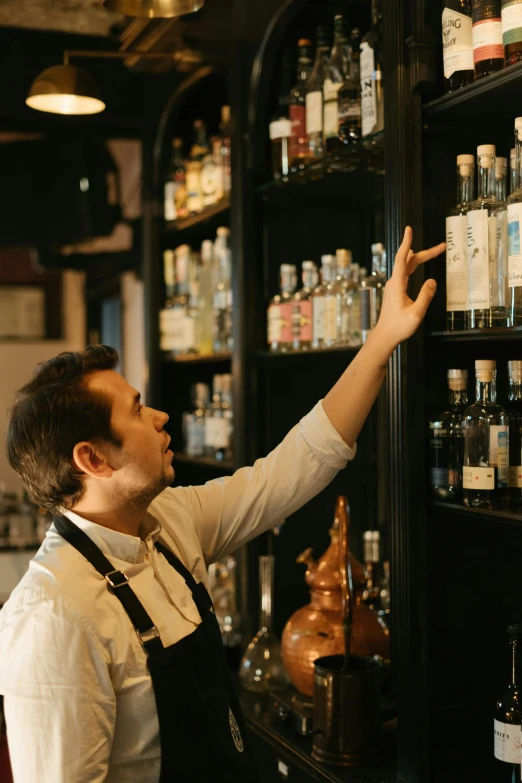 a man standing in front of a shelf filled with bottles, garnish, look at the details, staff, opening