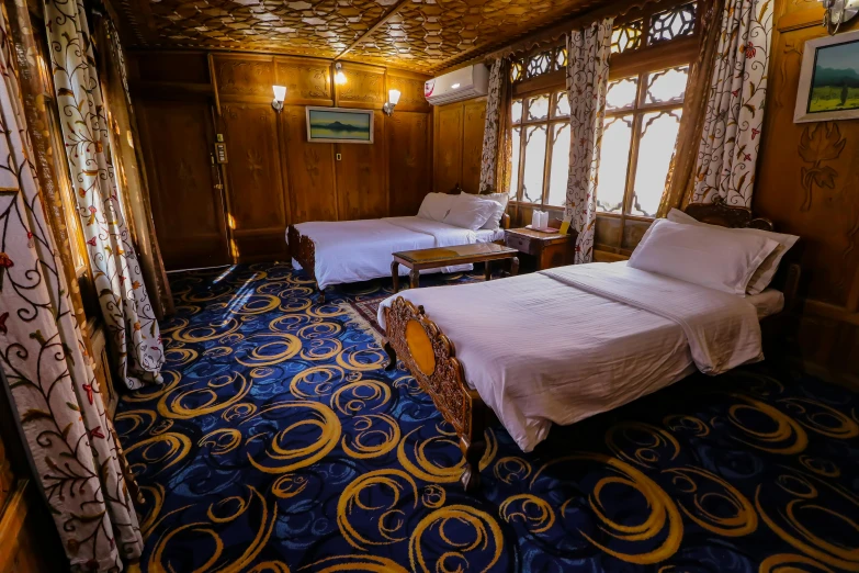 this is a bedroom with two beds on blue carpet and ornate ceiling