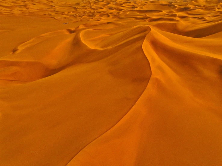 a person riding a surfboard on top of a sandy beach, inspired by Christo, pexels contest winner, surrealism, folds of fabric, on the orange surface of mars, moroccan, draped in silky gold