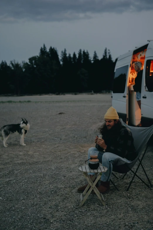 a man sitting in a chair next to a dog, a picture, unsplash contest winner, next to an rv, people at night, profile image, picnic