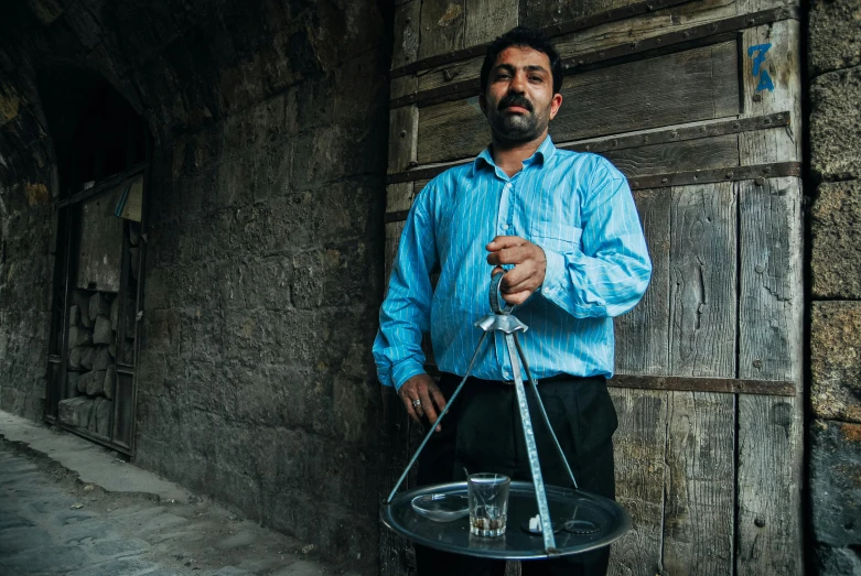 a man holds an item on the tray and stands next to a wall