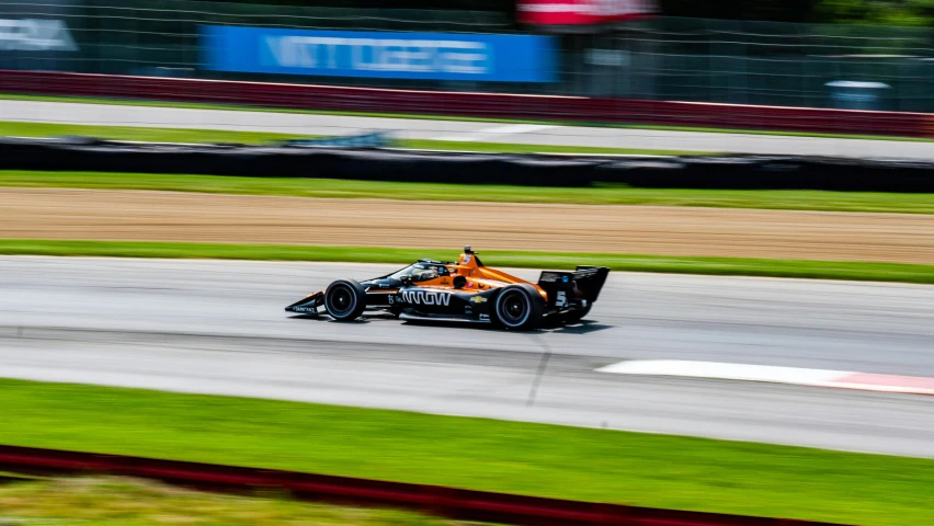 a man driving a race car on a track, orange and black, square, 🚿🗝📝, mason