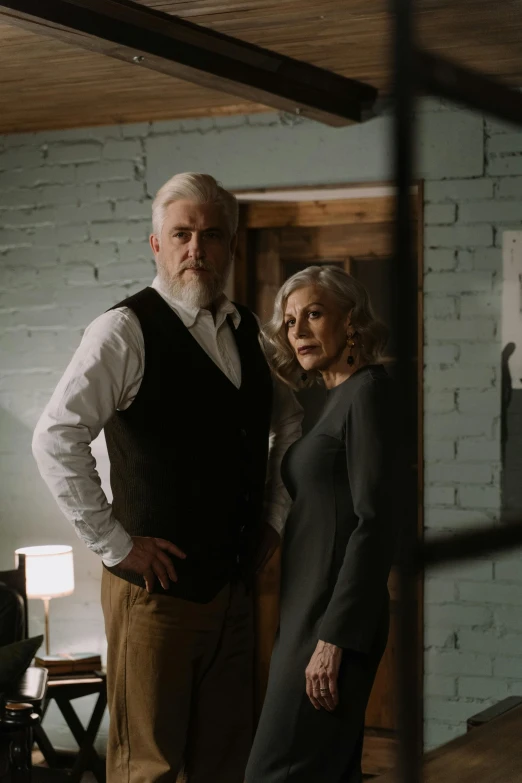 a man and a woman standing next to each other, a portrait, pexels contest winner, silver hair and beard, foreboding room, ( ( theatrical ) ), promotional image