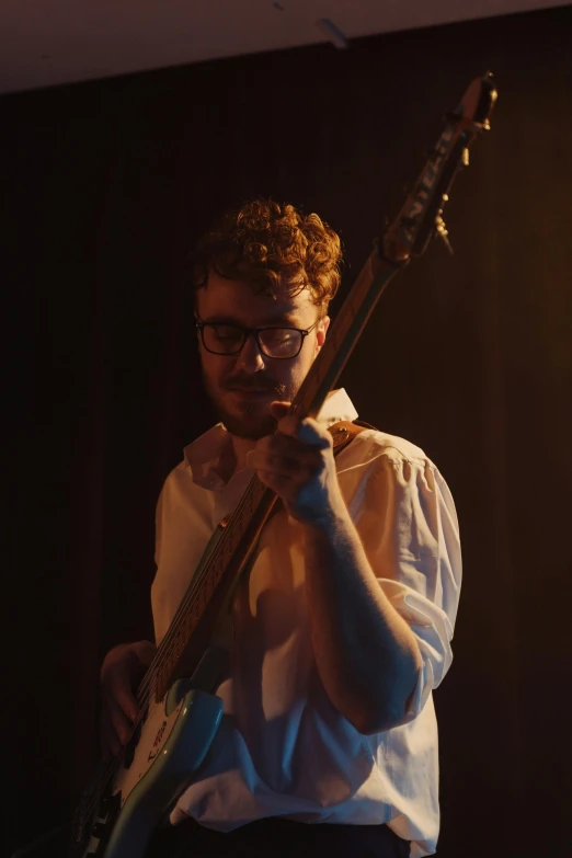 a man in a white shirt playing a guitar, justin roiland, moody lighting, bassist, sydney hanson