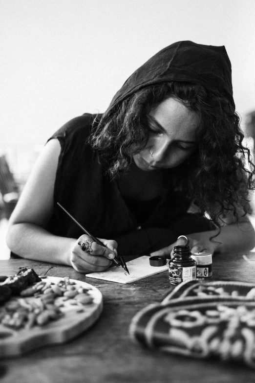 a woman writes on her paper while sitting at a table with pizzas