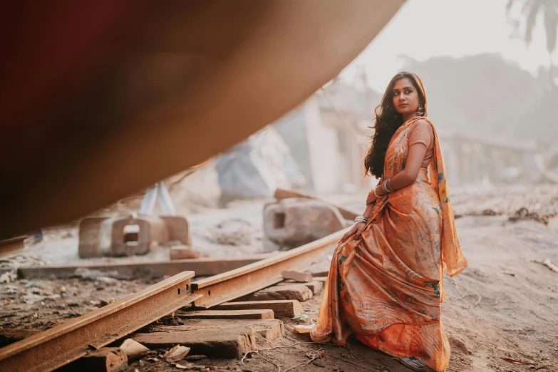 a woman in an orange sari sitting on a train track, pexels contest winner, standing elegantly, medium format. soft light, profile image, in a temple