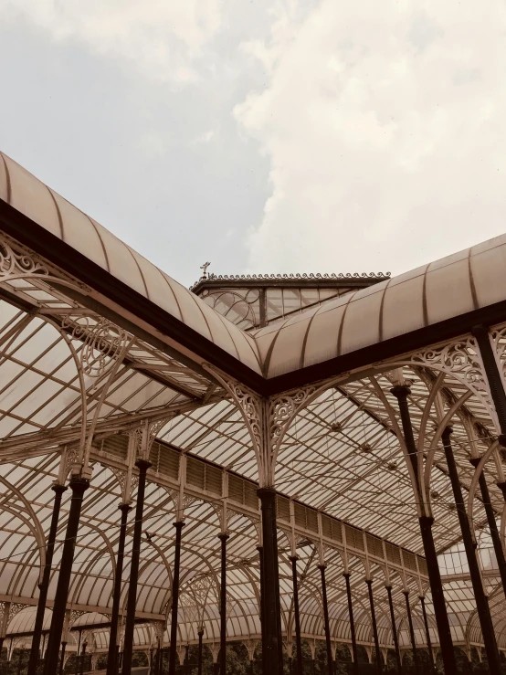 a large glass building with a clock on top of it, by Carey Morris, unsplash contest winner, art nouveau, mystical kew gardens, archways between stalagtites, photo taken on fujifilm superia, simple gable roofs