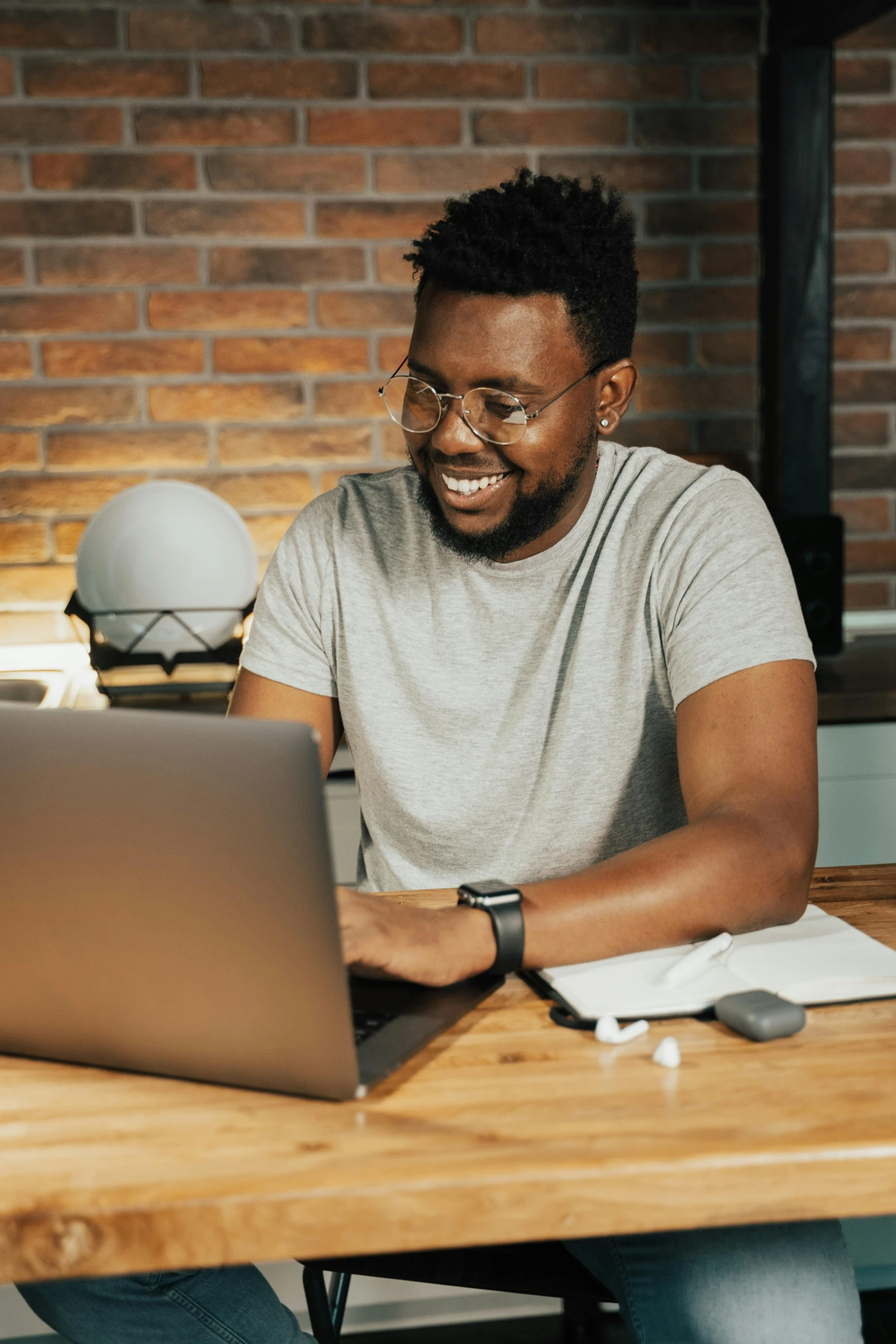 a man sitting at a table with a laptop, looking happy, multiple stories, thumbnail, black man