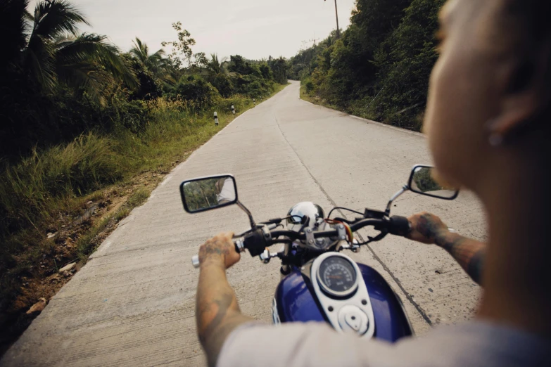 a person riding a motorcycle down a road near grass