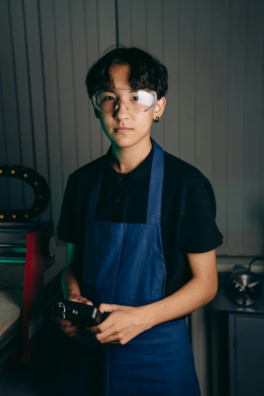 a man standing in a kitchen holding a camera, inspired by John Luke, wearing goggles, jinsung lim, aged 13, metal works