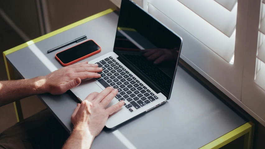 a man sitting at a desk using a laptop computer, by Carey Morris, pexels, bottom angle, maintenance, multiple stories, handheld